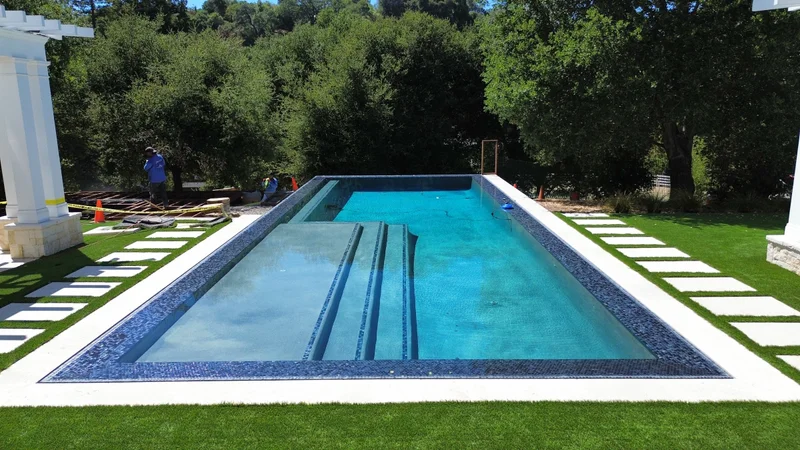 Overhead aerial of a custom lap pool, pergola, and turf-and-paver decking