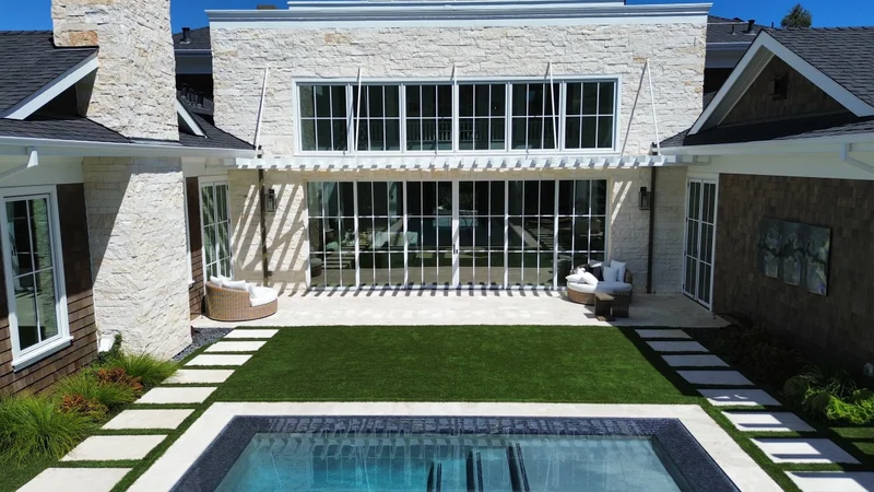 Aerial view of a finished modern home with a custom lap pool and landscaped yard