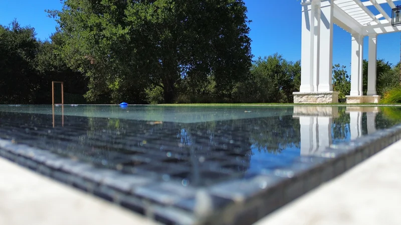 Close-up of shimmering pool water beside a white pergola