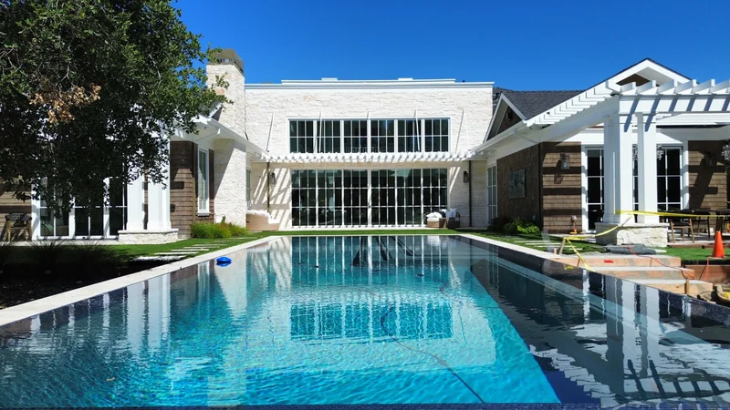 Low-angle view of a completed lap pool beside a contemporary home and pergola