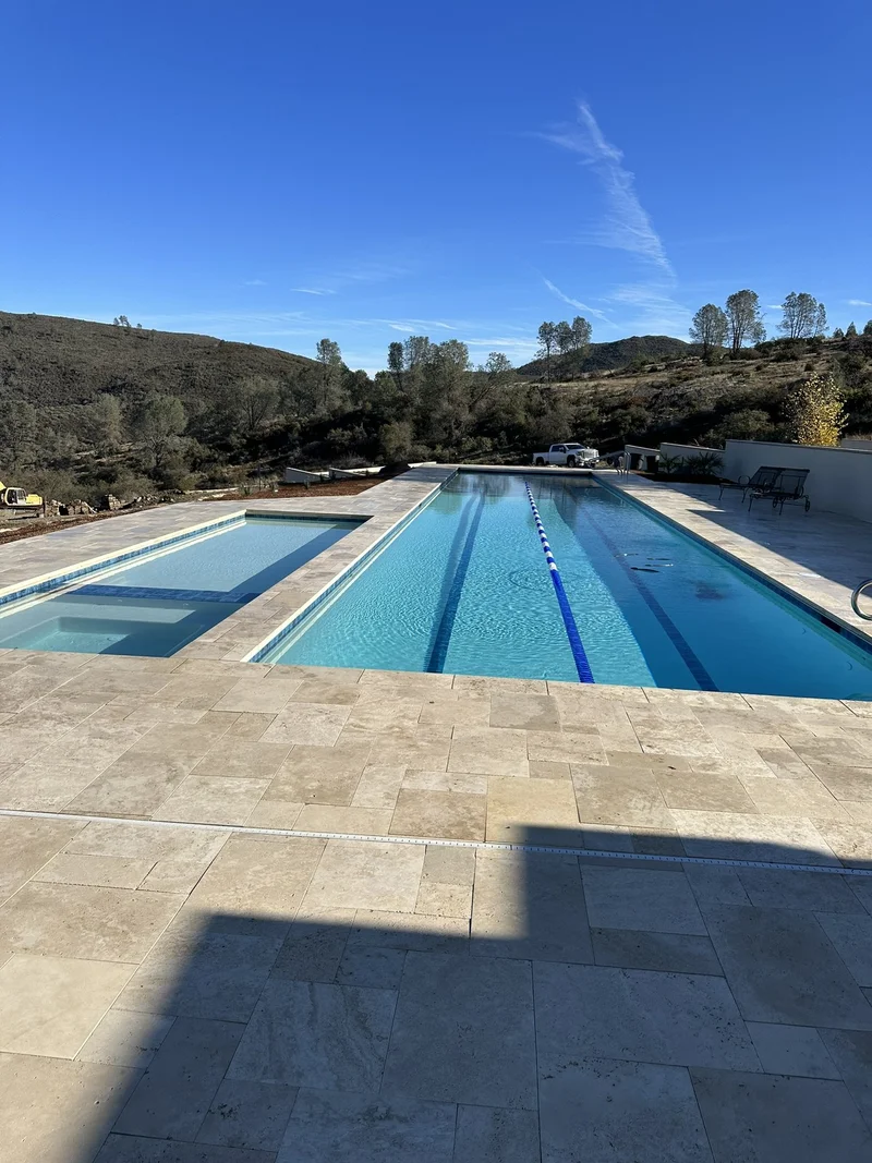 Custom lap pool with stone-and-concrete decking overlooking open hills