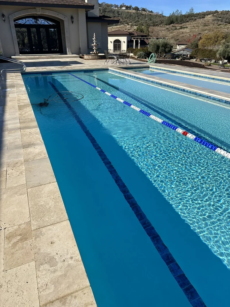 Finished lap pool with travertine deck and hillside views