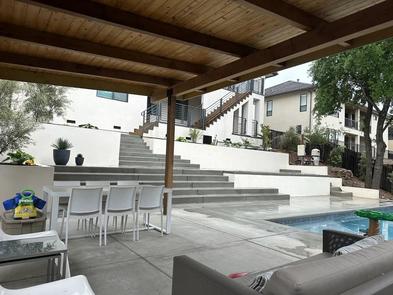 Pergola with a wood-slat ceiling and lounge seating beside the pool
