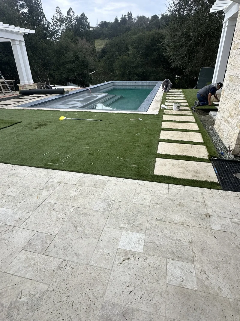 Manicured lawn, paver patio, and pergola surrounding the pool