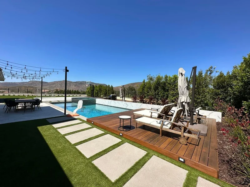 Backyard pool framed by turf and concrete hardscaping