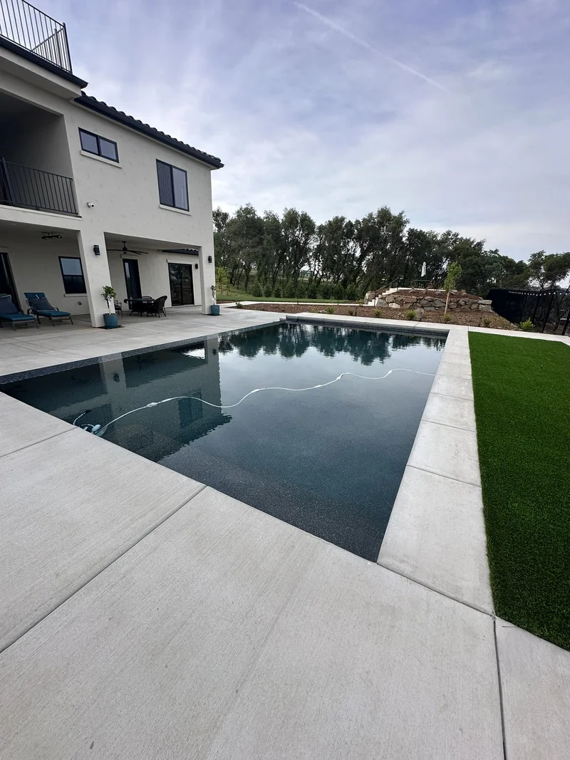 Tiered concrete steps and pool deck reflecting a contemporary home
