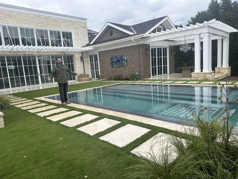 Pool deck with white pergola columns and a tiered concrete patio