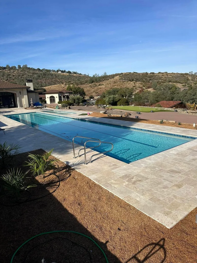 Resort-style pool with travertine deck on a hillside property