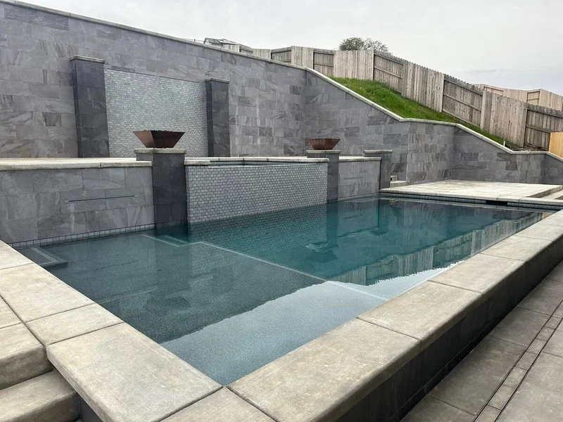 Completed luxury pool with stone wall and custom water features