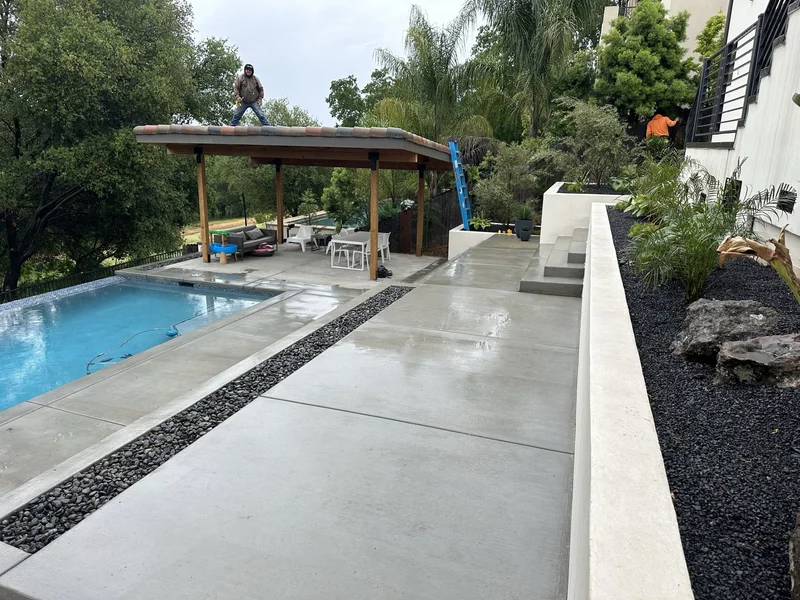 Freshly poured concrete pool deck and pergola during the build