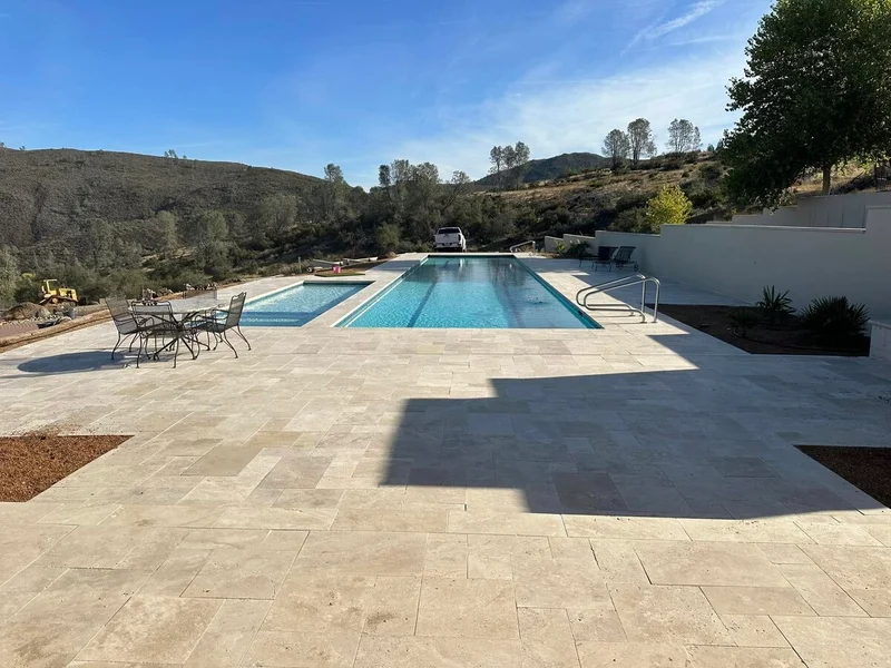 Expansive travertine patio surrounding custom pool